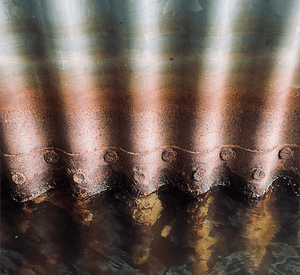 A rusty riveted seam in a culvert bridge.